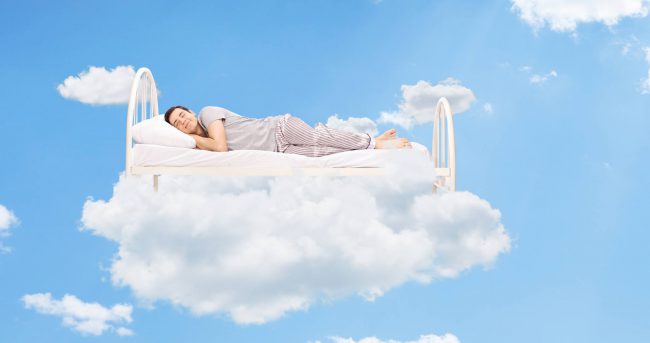 Man sleeping on a bed in the clouds high up in the sky